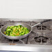 A Vollrath Wear-Ever aluminum non-stick fry pan filled with broccoli and corn on a stove.
