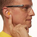 A man wearing safety glasses and an orange 3M earplug.