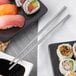 A plate of sushi rolls with Acopa stainless steel chopsticks.