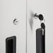 The hinged door handles of a Regency stainless steel wall cabinet with a key in the lock.