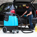 A woman using a Mytee Grand Prix heated extractor vacuum to clean a car trunk.
