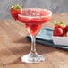 A glass of Island Oasis strawberry beverage mix with a strawberry garnish.