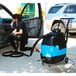 A woman in a black shirt using a Mytee Lite carpet extractor to vacuum a car.