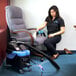 A woman using a Mytee heated upholstery spotter to clean a chair.