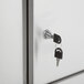 The sliding metal doors of a Regency stainless steel wall cabinet with a key in the keyhole.