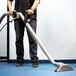 A person using a Mytee Bentley titanium wand to vacuum a carpet.