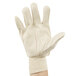 A person's hand wearing a large Cordova white poly/cotton blend canvas glove.