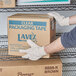 A person wearing Cordova canvas gloves holding a box.