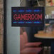 A Choice LED rectangular gameroom sign with lights on it hanging in a window.