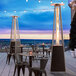 A black Backyard Pro portable patio heater with a glass tube on an outdoor patio with chairs and a table.