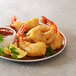 A plate of Golden Dipt fried shrimp with lemon wedges and sauce.