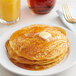 A stack of Golden Dipt pancakes with butter and syrup on top on a plate.