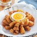 A basket of fried onion rings with a sauce.