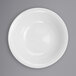 A close-up of an International Tableware Dover white porcelain fruit bowl with a white rim.