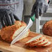 A person using a Dexter-Russell 36008G bread knife to slice a loaf of bread.