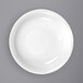 A close-up of an International Tableware white porcelain soup bowl with a rolled edge.