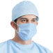 A man wearing blue scrubs and a blue 3-ply protective face mask.