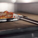 A GI Metal pan gripper lifting a rectangular pizza pan with a pizza in it.