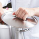 A hand holding a Vollrath stainless steel domed lid on a silver pot.