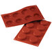 A red silicone baking mold with eight flan compartments.