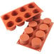A Silikomart orange silicone baking mold with 8 cylindrical cavities.