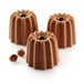 A close-up of three chocolate canneles in a Silikomart silicone baking mold.