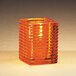 An orange ribbed glass Sterno Kelly square liquid candle holder with a light inside.