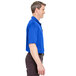 The back of a man wearing a royal blue Henry Segal performance polo shirt.
