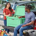 A man and woman sitting on the back of a truck with a CaterGator seafoam cooler.