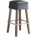 A Lancaster Table & Seating Sofia wood backless bar stool with a black cushion.