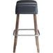 A Lancaster Table & Seating Sofia wood backless bar stool with black vinyl seat.