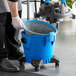 A person wearing gloves uses a Lavex wet / dry vacuum toolkit to clean a blue bucket.