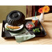 A black tray with a pedestal bowl filled with food on a table.