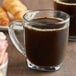 A glass mug of Caribou Blend coffee on a table.