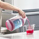 A person pouring Noble Chemical Arctic ice machine cleaner from a jug into a measuring cup on a kitchen counter.