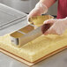 A person in gloves using an Ateco stainless steel number 1 cutter to cut a cake.