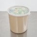 A beige Cambro round polypropylene crock with a clear lid filled with food.