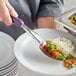 A person using a Vollrath Jacob's Pride perforated basting spoon to serve vegetables on a plate.