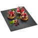 A Solia slate black tray with fruit tarts and berries on it.