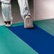 A person wearing white shoes standing on a blue Cactus Mat contaminate control dry mat.