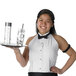 A woman wearing a Henry Segal white halter top tuxedo shirt holding a tray with a drink and a straw.