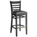 A Lancaster Table & Seating black wood ladder back bar stool with black vinyl seat on a white background.
