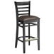 A black Lancaster Table & Seating wood bar stool with dark brown vinyl seat.