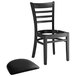 A Lancaster Table & Seating black wood ladder back chair with a detached black vinyl seat.