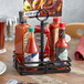 An American Metalcraft wrought iron rectangular condiment caddy holding hot sauce bottles on a table.