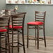A Lancaster Table & Seating wood ladder back bar stool with a detached red vinyl seat.