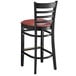 A black Lancaster Table & Seating wood bar stool with a burgundy vinyl seat.