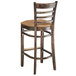 A Lancaster Table & Seating wooden bar stool with a light brown vinyl seat.