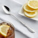 An Acopa stainless steel iced tea spoon with a lemon slice in a glass of iced tea.