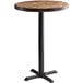A Lancaster Table & Seating round wooden table with a black cast iron base.